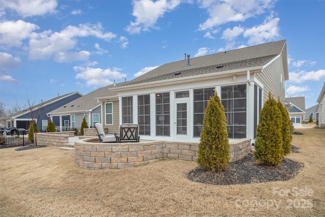 back of property featuring fence, a sunroom, stone siding, roof with shingles, and a patio area