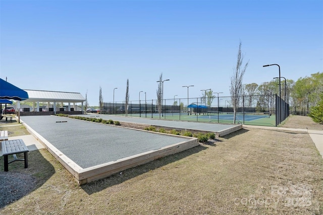 view of property's community with a tennis court and fence