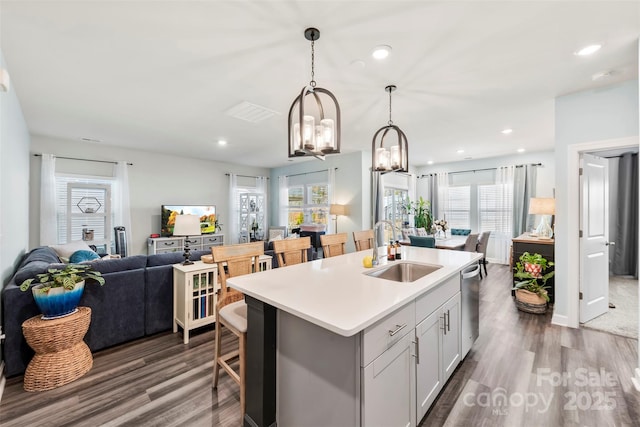 kitchen with dark wood finished floors, a center island with sink, open floor plan, and a sink