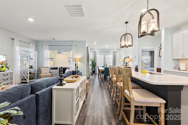 kitchen featuring open floor plan, visible vents, a center island with sink, and a sink