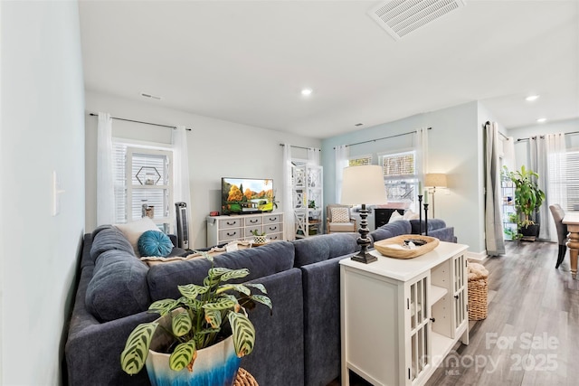 living area featuring plenty of natural light, light wood-type flooring, visible vents, and recessed lighting