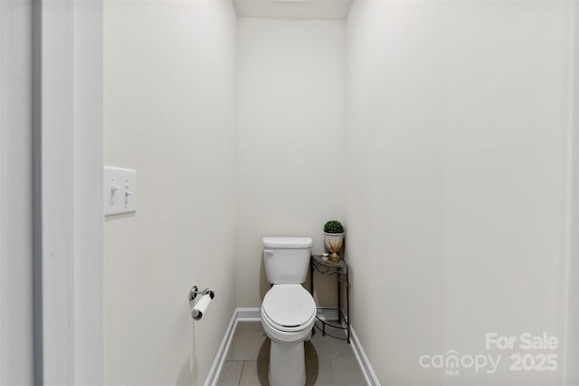 bathroom with toilet, tile patterned flooring, and baseboards