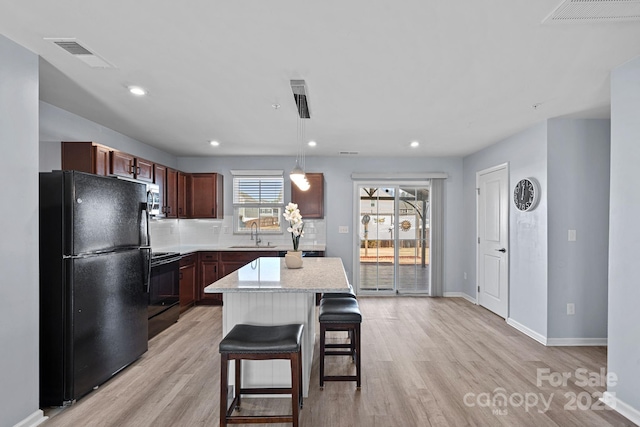 kitchen featuring light wood-style flooring, visible vents, backsplash, and black appliances