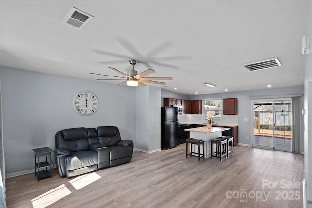 living room featuring light wood finished floors, baseboards, and visible vents