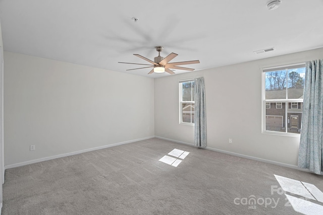 carpeted spare room featuring ceiling fan, visible vents, and baseboards