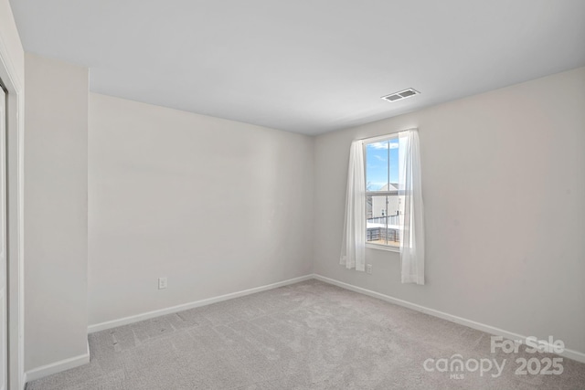 spare room featuring carpet, visible vents, and baseboards