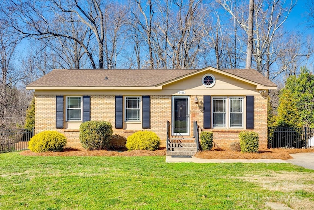 single story home with brick siding, fence, and a front yard