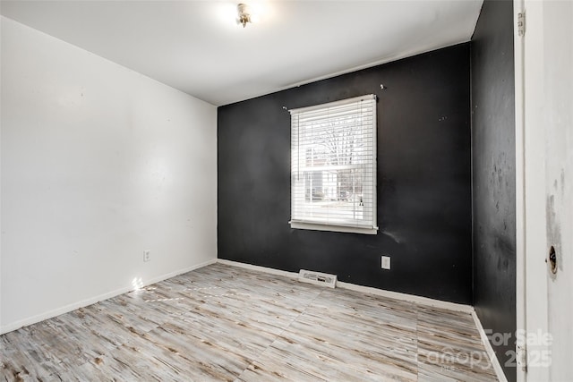 unfurnished room featuring visible vents, baseboards, and wood finished floors