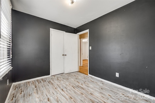 unfurnished bedroom featuring light wood finished floors and a closet