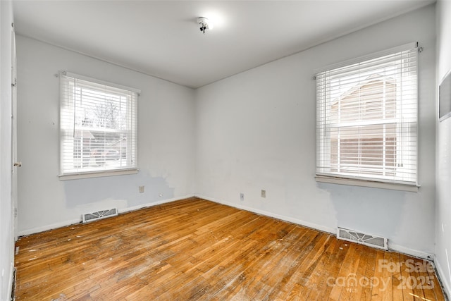 spare room with baseboards, visible vents, and hardwood / wood-style floors