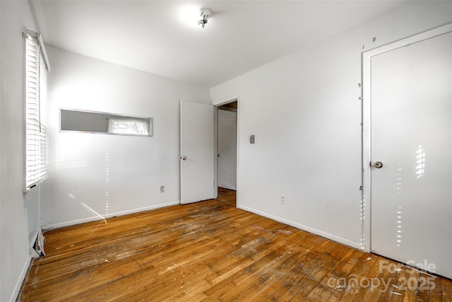 unfurnished bedroom with hardwood / wood-style flooring and baseboards