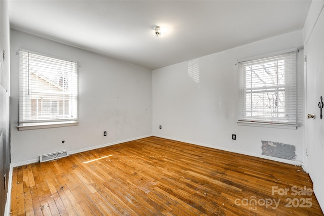 spare room featuring hardwood / wood-style flooring, baseboards, and visible vents