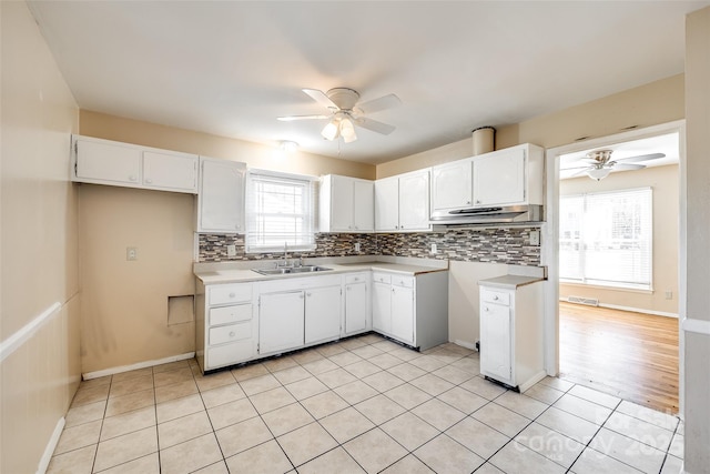 kitchen with tasteful backsplash, ceiling fan, light countertops, white cabinetry, and a sink