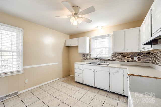 kitchen featuring light countertops, white cabinets, visible vents, and a sink