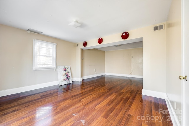 unfurnished room with visible vents, baseboards, and wood finished floors