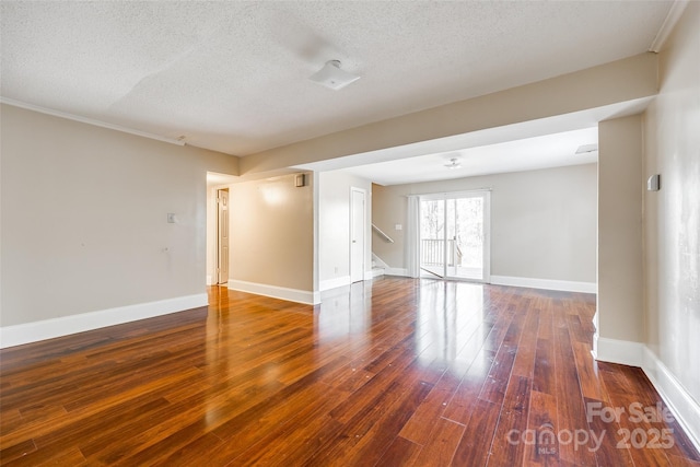 empty room with stairway, baseboards, a textured ceiling, and hardwood / wood-style floors