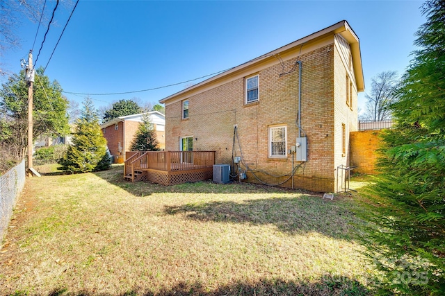 back of house with fence, a deck, a lawn, and brick siding