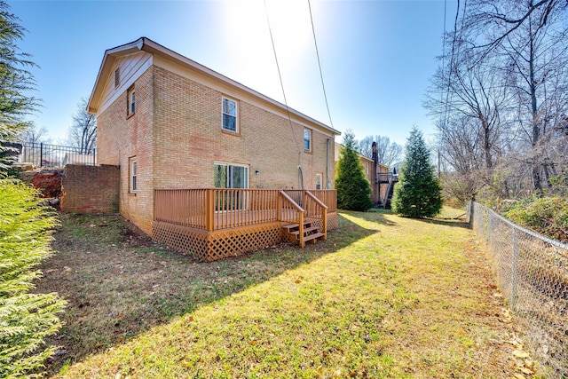 rear view of house with brick siding, a fenced backyard, a lawn, and a wooden deck