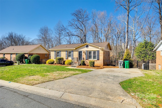 ranch-style home featuring brick siding, fence, driveway, and a front lawn