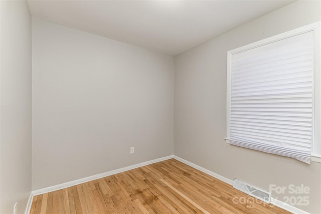 empty room with visible vents, light wood-style flooring, and baseboards