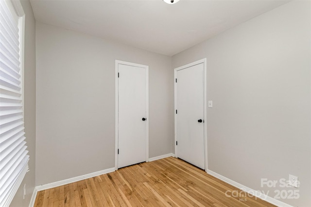 unfurnished room with baseboards and light wood-style floors