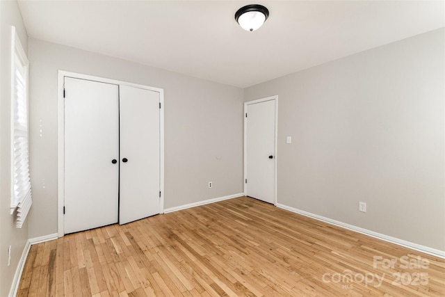 unfurnished bedroom featuring a closet, light wood-style flooring, and baseboards