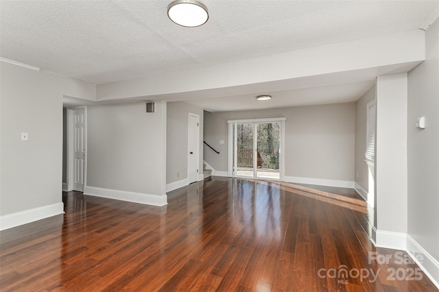empty room with stairway, baseboards, and wood-type flooring