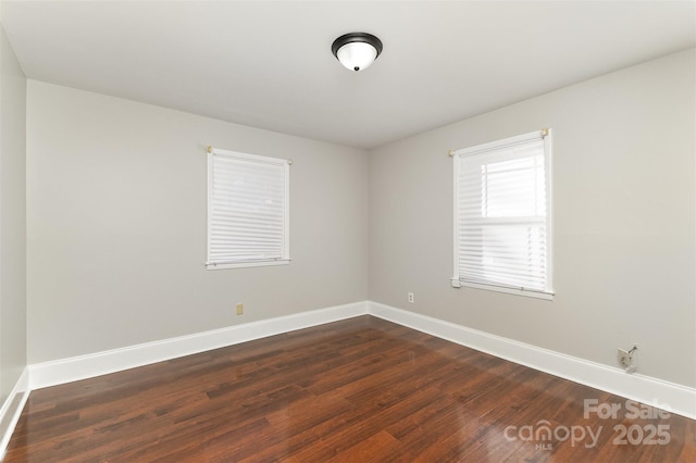 spare room with dark wood-style floors and baseboards