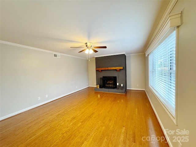 unfurnished living room with ornamental molding, a brick fireplace, wood finished floors, and baseboards