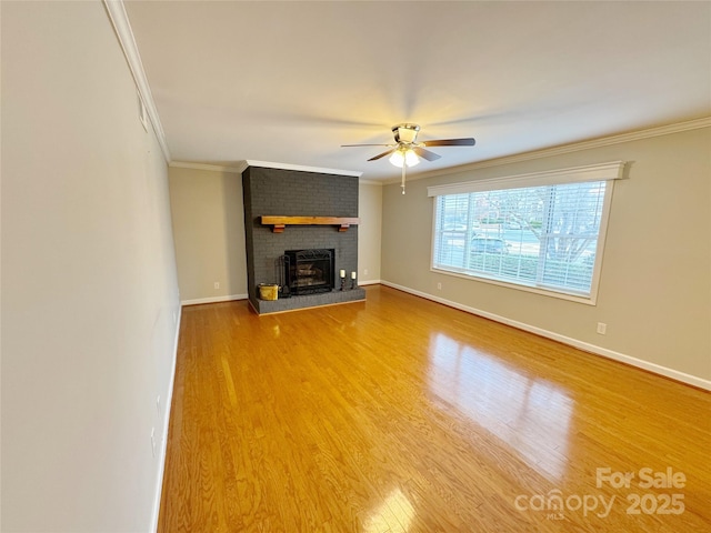 unfurnished living room featuring ornamental molding, a brick fireplace, wood finished floors, and baseboards