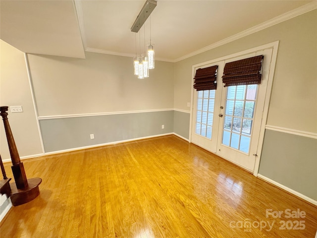 unfurnished room featuring a notable chandelier, wood finished floors, baseboards, french doors, and crown molding