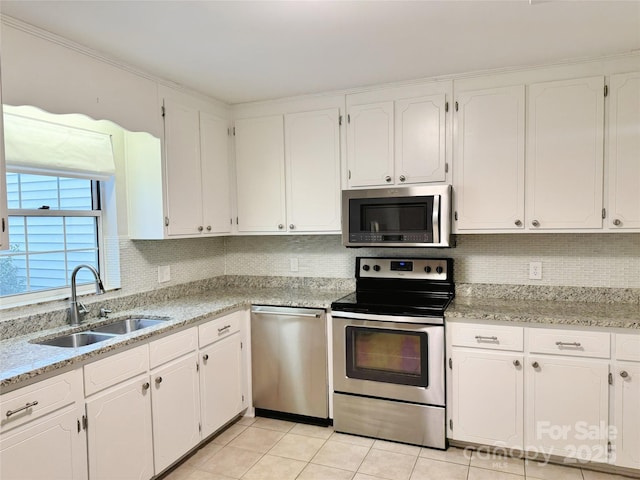 kitchen featuring tasteful backsplash, appliances with stainless steel finishes, light tile patterned flooring, white cabinets, and a sink