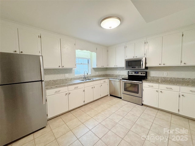 kitchen with white cabinets, light stone countertops, stainless steel appliances, and a sink