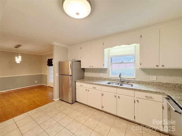 kitchen with light tile patterned floors, appliances with stainless steel finishes, a sink, white cabinetry, and backsplash