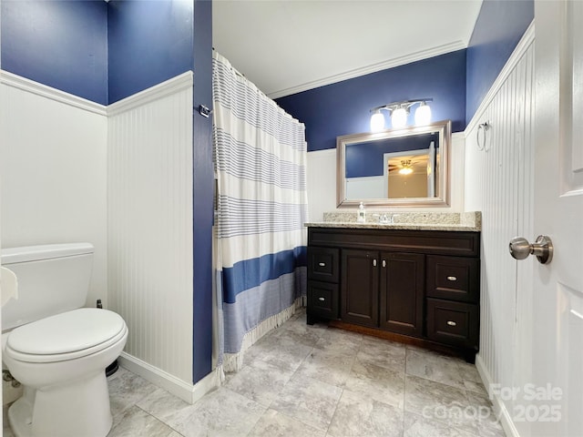 bathroom with curtained shower, toilet, vanity, baseboards, and crown molding