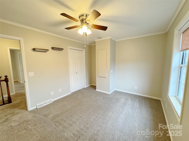 unfurnished bedroom with baseboards, carpet floors, visible vents, and crown molding