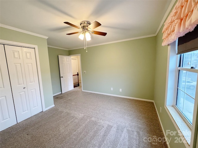 unfurnished bedroom with baseboards, ceiling fan, crown molding, carpet floors, and a closet