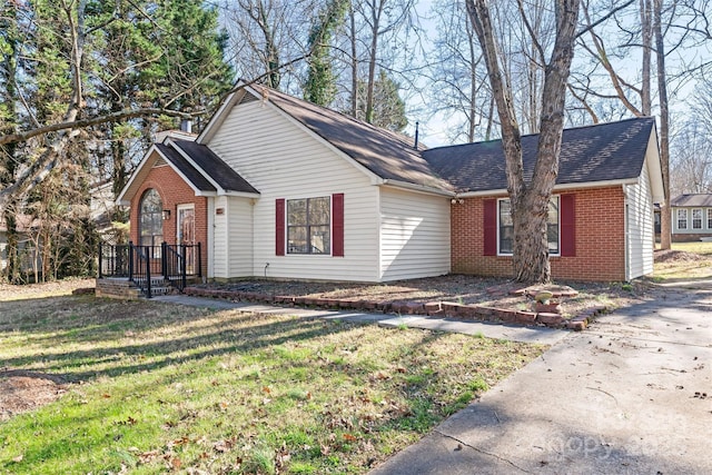 view of front of house with brick siding, a front lawn, and roof with shingles