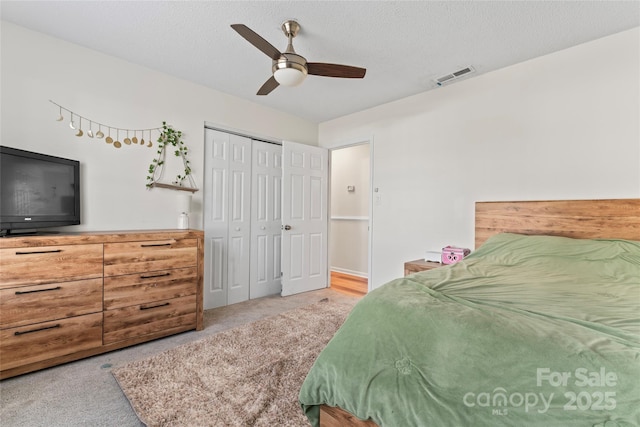 bedroom with a closet, visible vents, carpet floors, and a textured ceiling