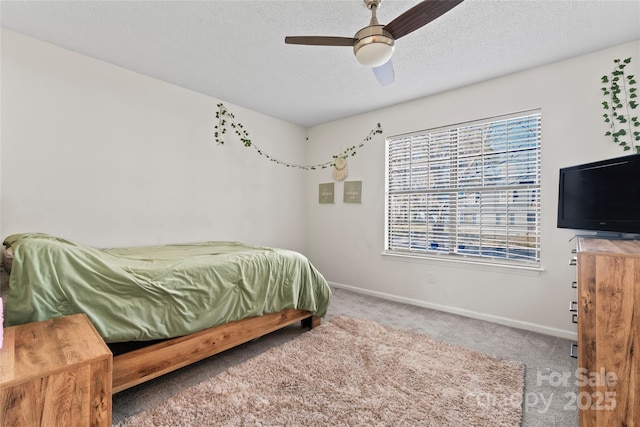 carpeted bedroom featuring ceiling fan, baseboards, and a textured ceiling