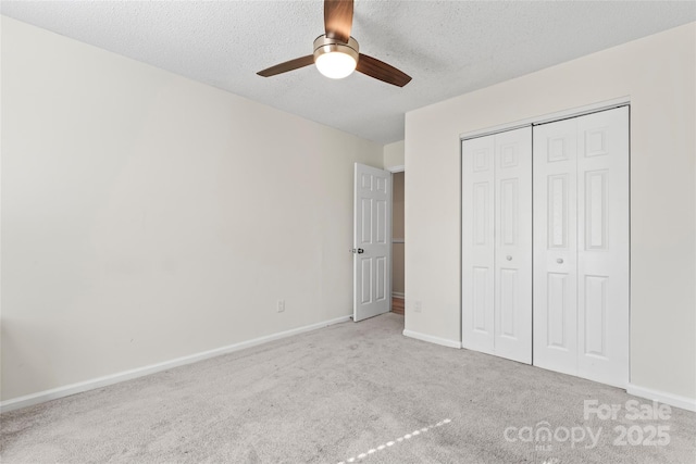 unfurnished bedroom featuring a ceiling fan, baseboards, carpet floors, a closet, and a textured ceiling