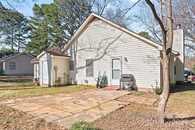 back of property with a shed, entry steps, a chimney, an outbuilding, and a patio