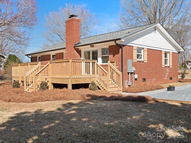 back of house featuring a deck, brick siding, roof with shingles, crawl space, and a chimney