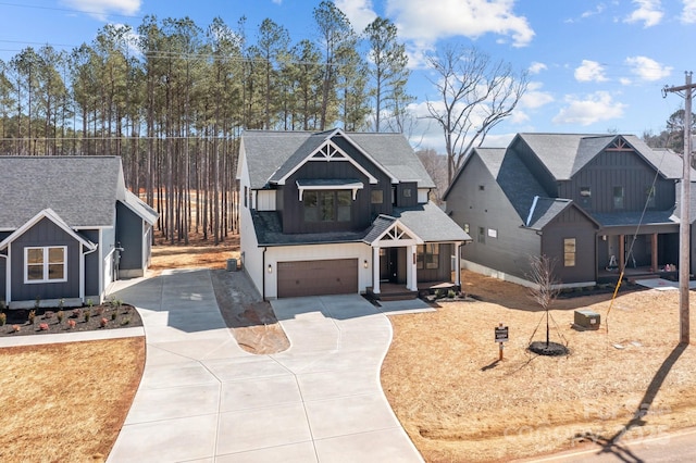 view of front of home with concrete driveway, board and batten siding, an attached garage, and roof with shingles