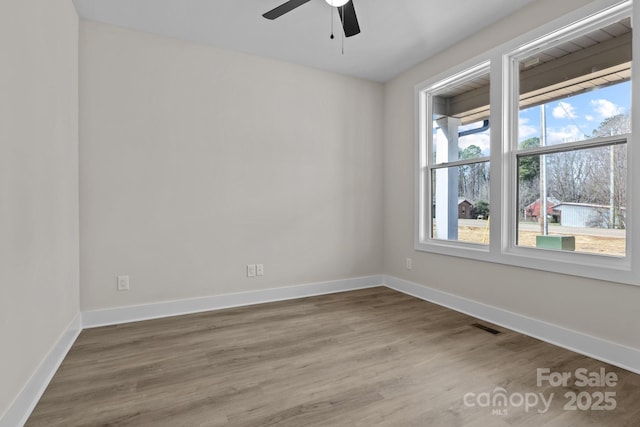 empty room with visible vents, baseboards, ceiling fan, and wood finished floors