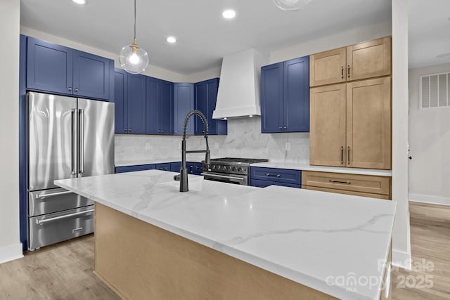 kitchen with visible vents, blue cabinetry, custom exhaust hood, and high quality appliances