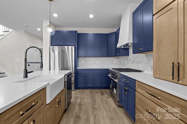 kitchen with blue cabinetry, high end appliances, a sink, and tasteful backsplash