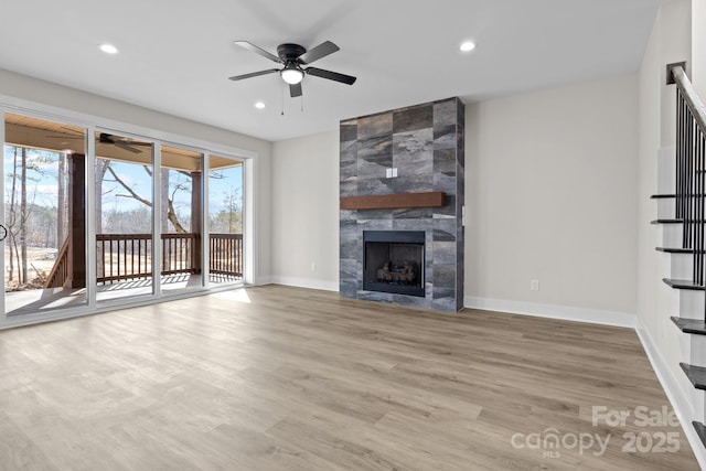 unfurnished living room featuring recessed lighting, baseboards, a tiled fireplace, and wood finished floors