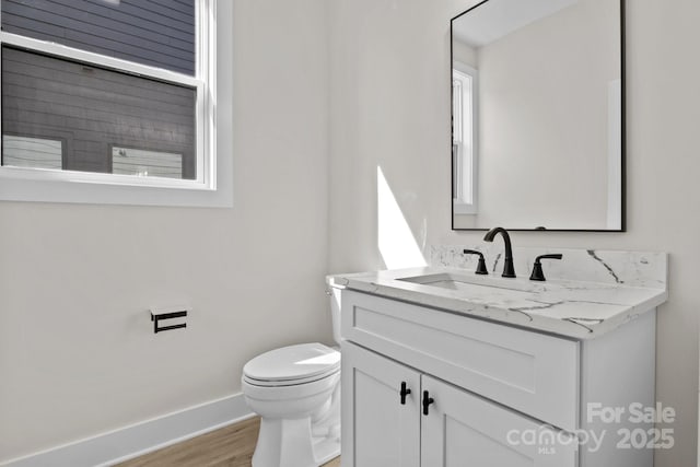 bathroom featuring wood finished floors, vanity, toilet, and baseboards