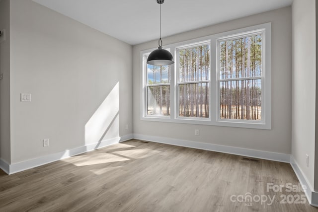 unfurnished dining area featuring visible vents, baseboards, and wood finished floors